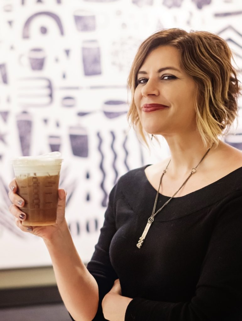 Kim holding coffee and ready to help you with your website.